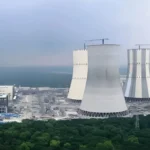 Industrial cooling towers near coastline.